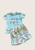 Children's blue t-shirt with van graphic and striped shorts on a beige background