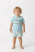 Child wearing a light blue t-shirt with a van graphic and striped shorts on a white background