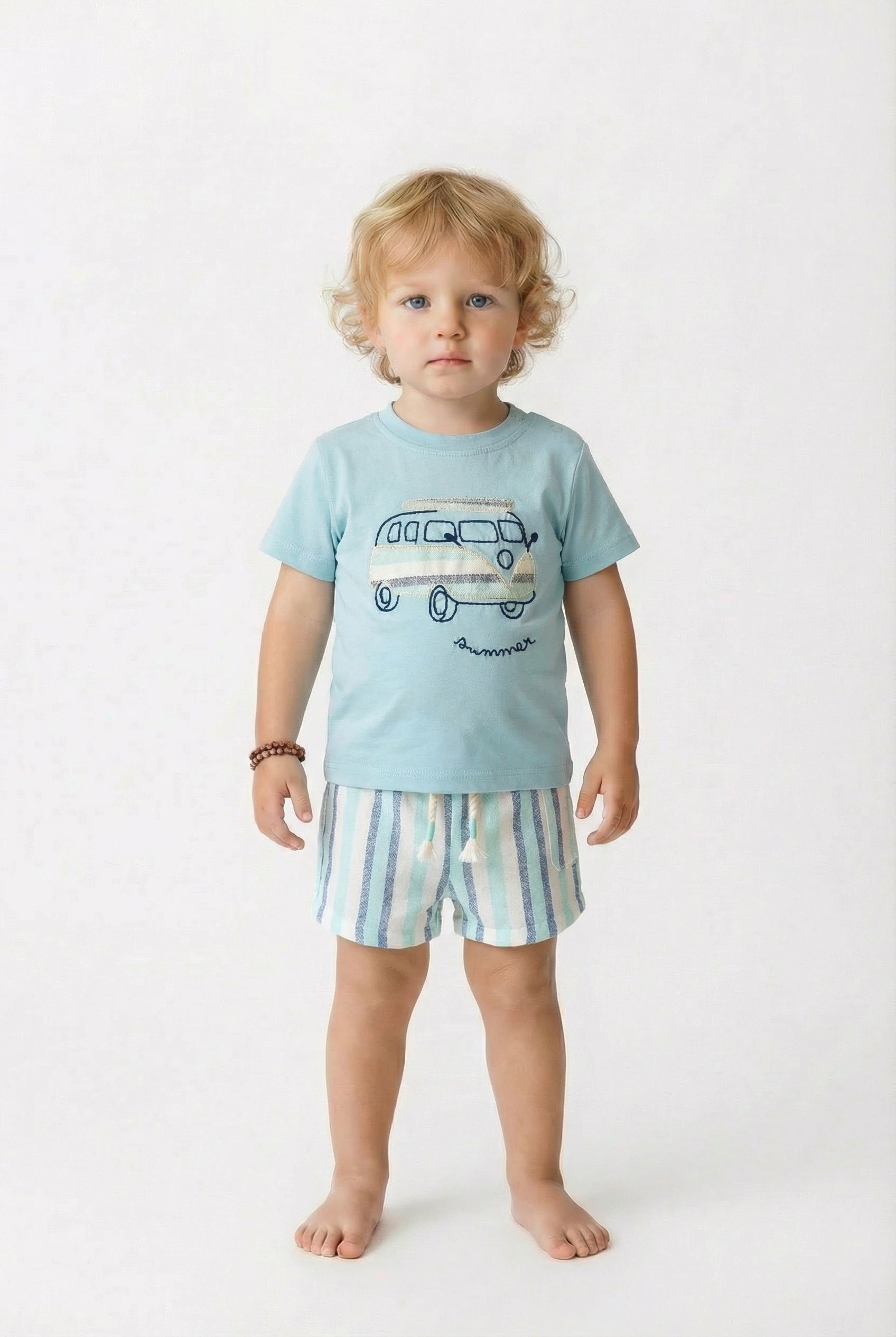 Child wearing a light blue t-shirt with a van graphic and striped shorts on a white background