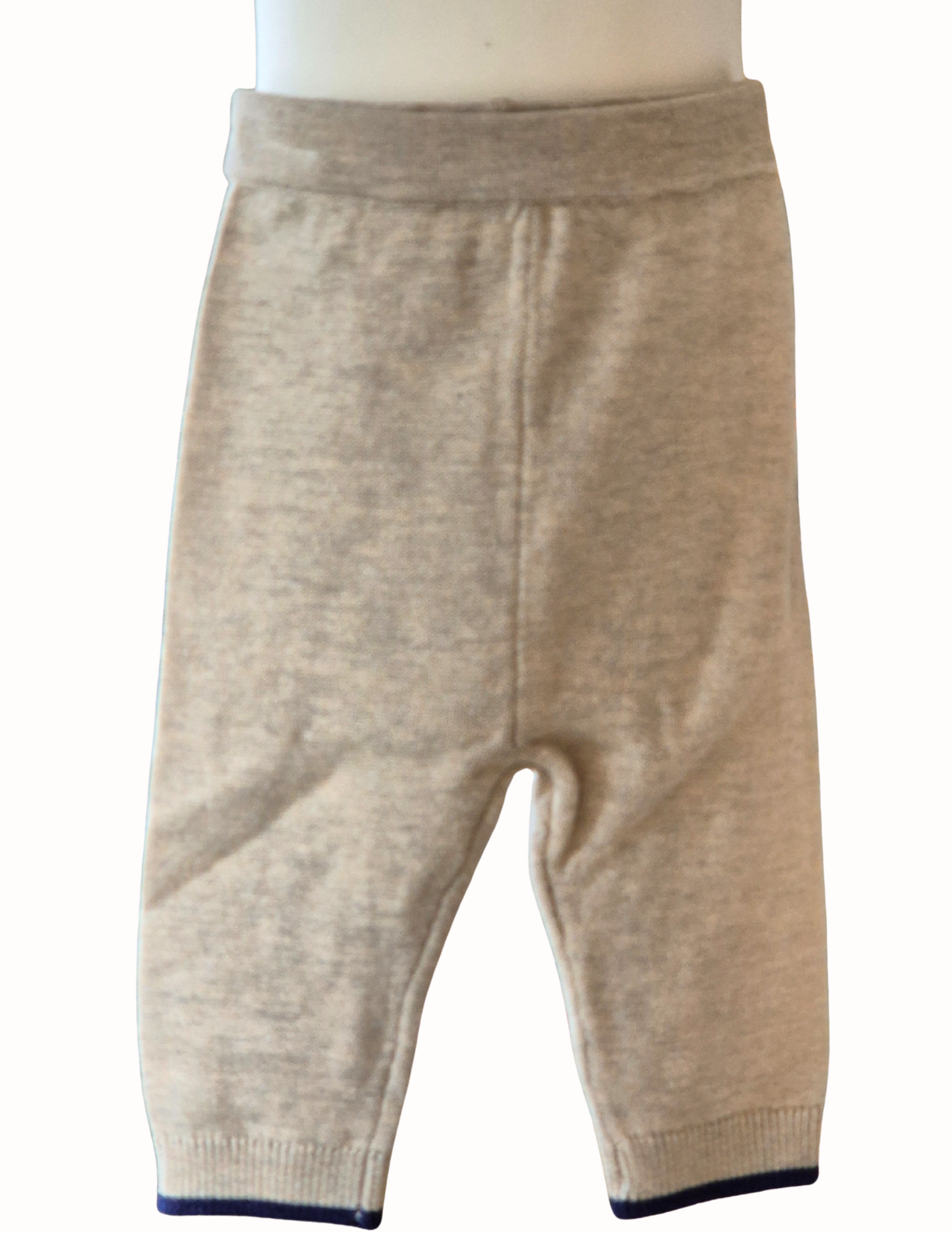 Beige knitted trousers with blue hem time part of the 2 piece set on a white background.

