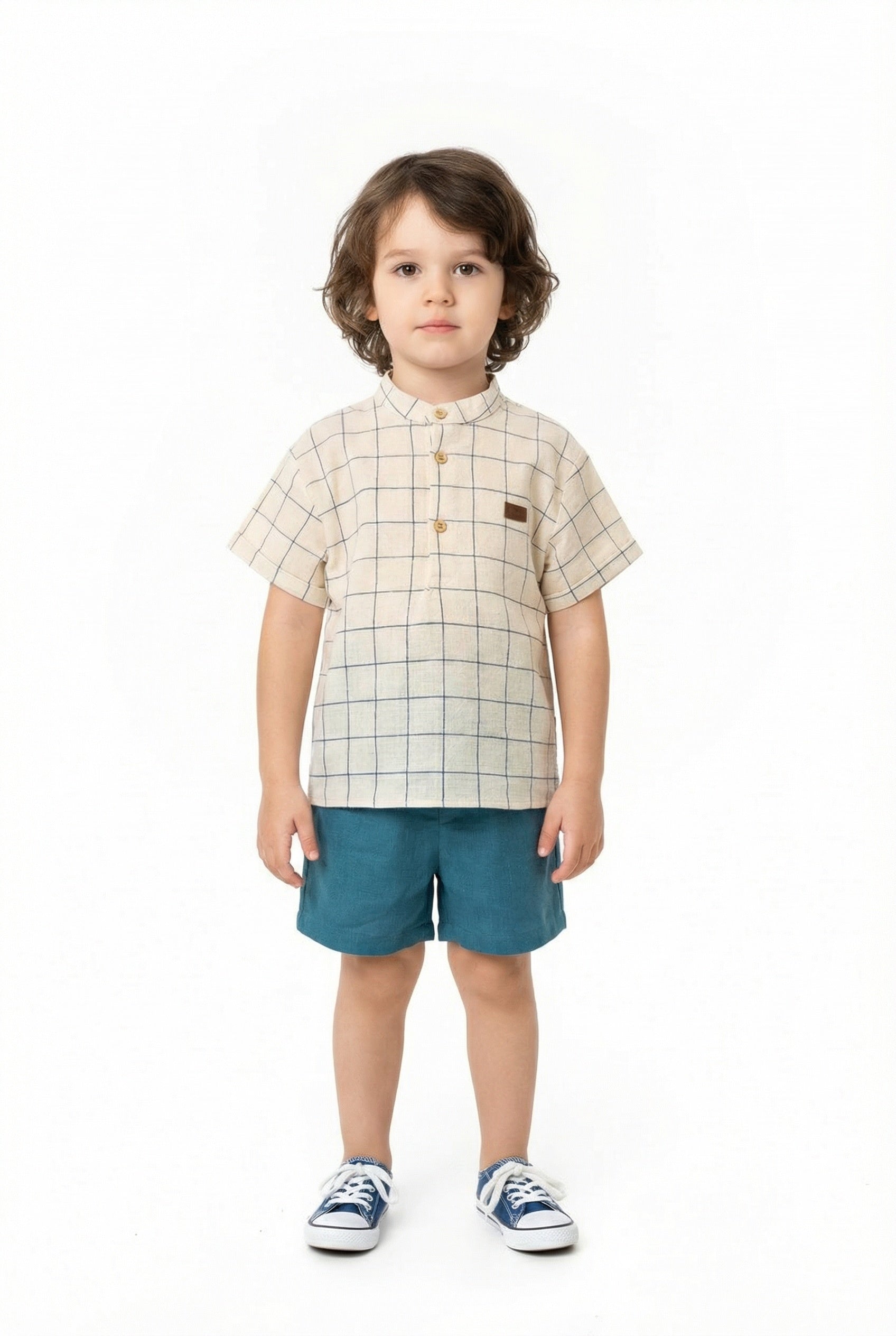 Child wearing a checkered shirt and blue shorts on a white background