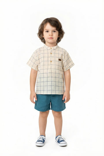Child wearing a checkered shirt and blue shorts on a white background