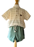 Children's outfit with checkered shirt and green shorts on a mannequin against a white background