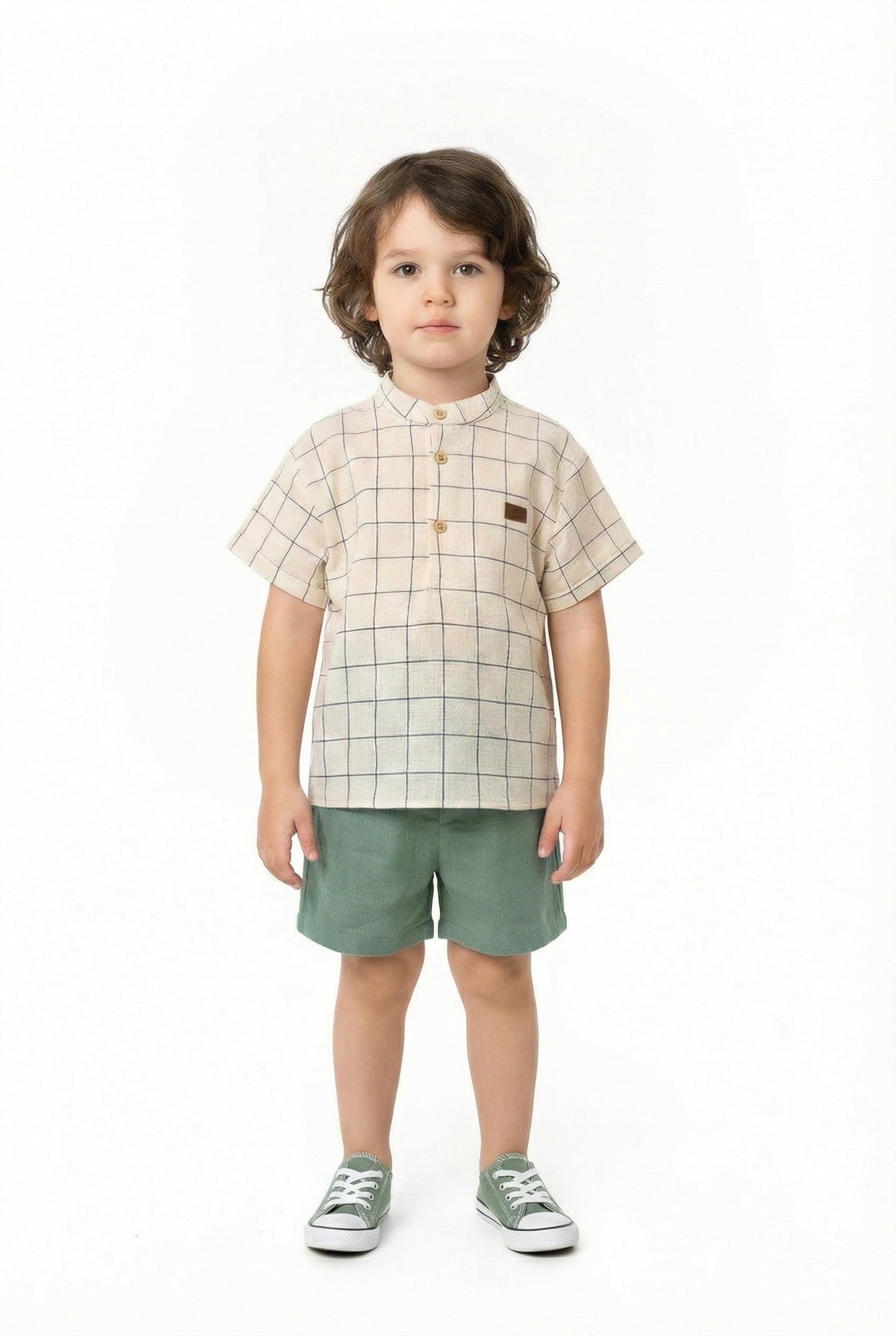 Child wearing a checkered shirt and green shorts on a white background