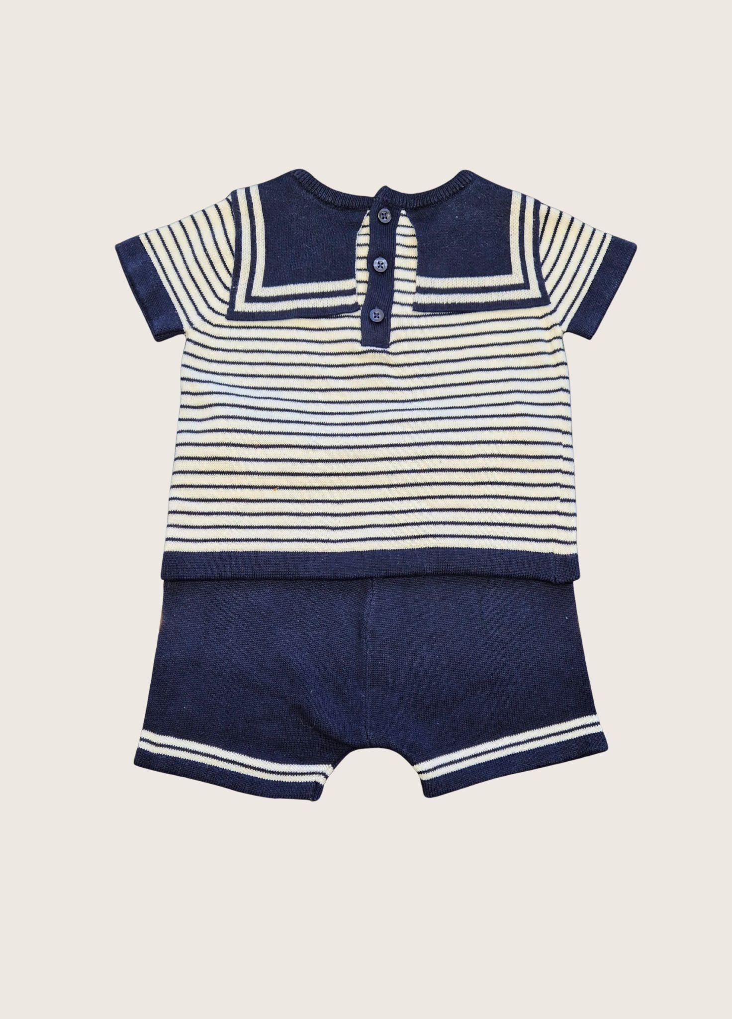 Navy and white striped baby suit with short sleeves on a beige background