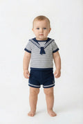 Baby wearing a striped sailor outfit on a white background