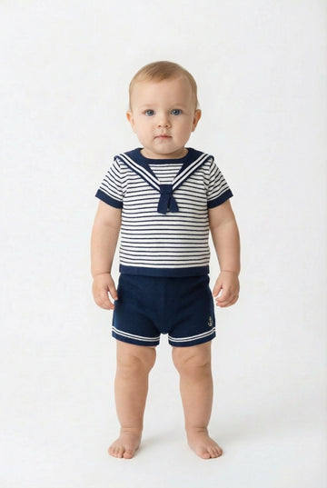 Baby wearing a striped sailor outfit on a white background