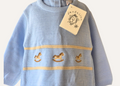 Close up detail of rocking horse motif on a baby blue knitted romper from Dandelion