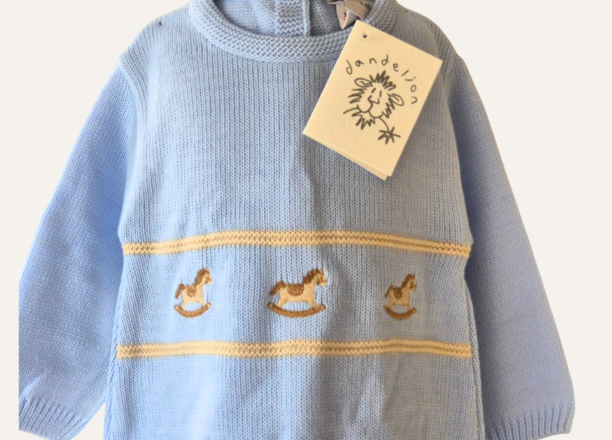 Close up detail of rocking horse motif on a baby blue knitted romper from Dandelion