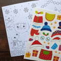 Coloring sheet with snowman outline and sticker sheet with festive elements on a wooden surface.