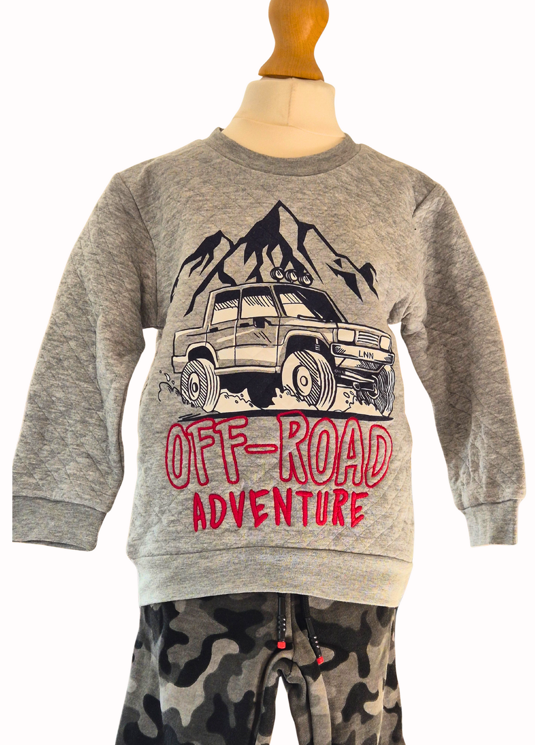 Children's outfit with gray sweatshirt and camouflage pants featuring 'Off-Road Adventure' text on a white background.
