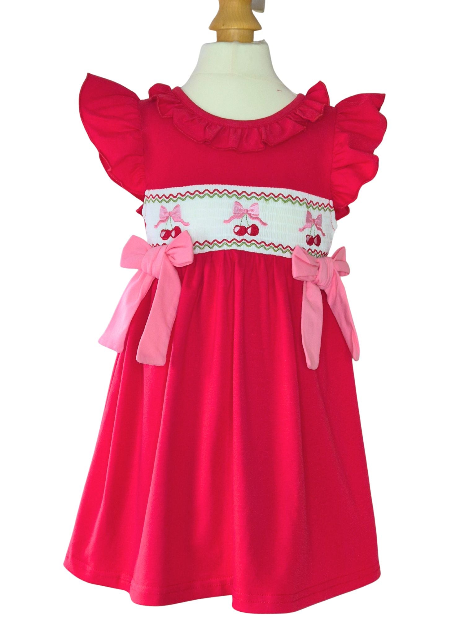 Red dress with pink bows and cherry details on a mannequin against a white background