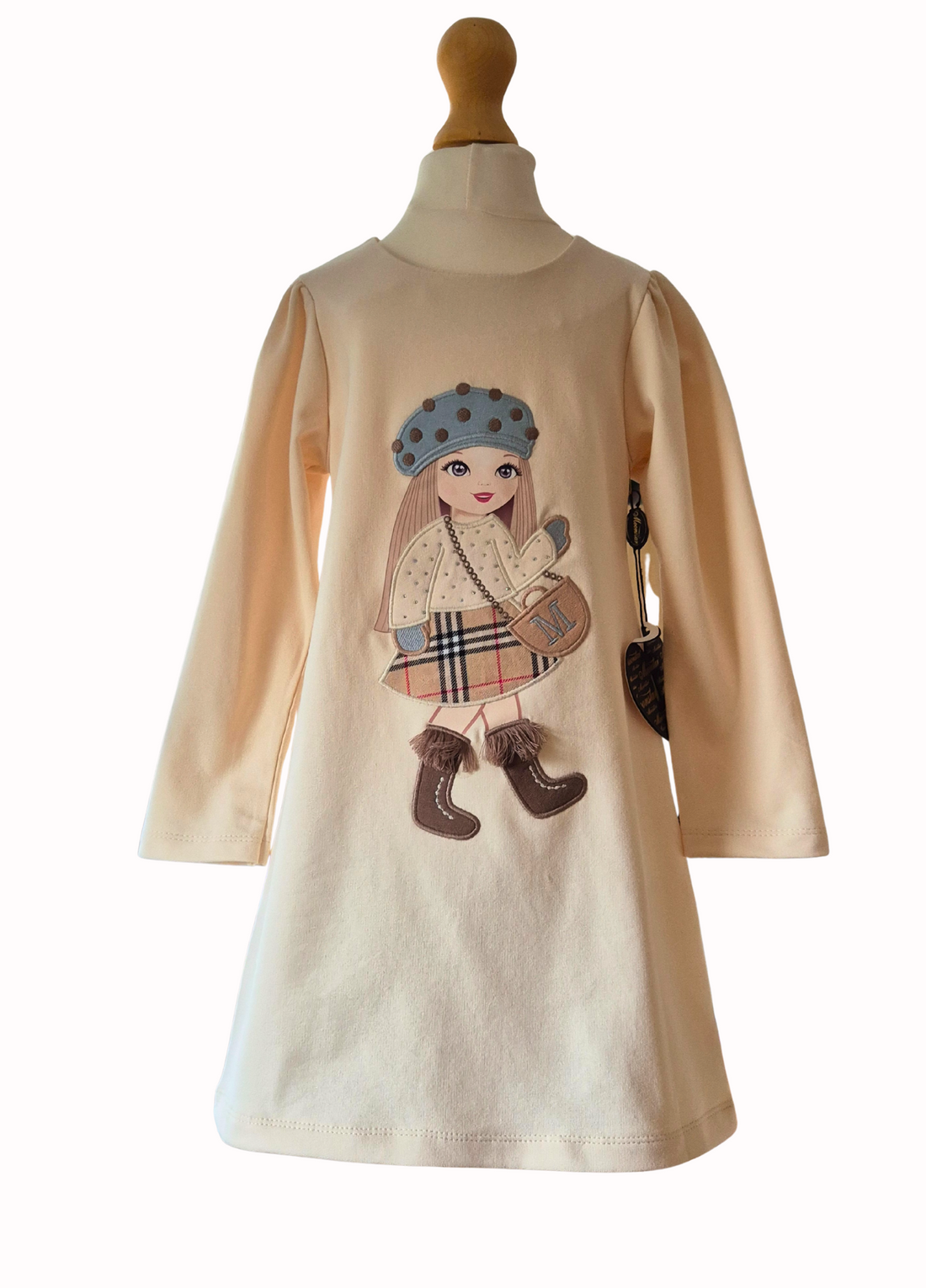 Cream dress with a large doll motif in the centre with hat, sparkle top, checked skirt and fringed boots on a white background.