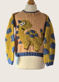 Knitted sweater with a dinosaur design on a mannequin against a white background