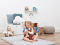 Child playing with toys in a room with a white wall and wooden floor.