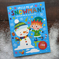 Children's activity book titled 'Dress Me Up Snowman' with a snowman and elf illustration on a wooden surface.
