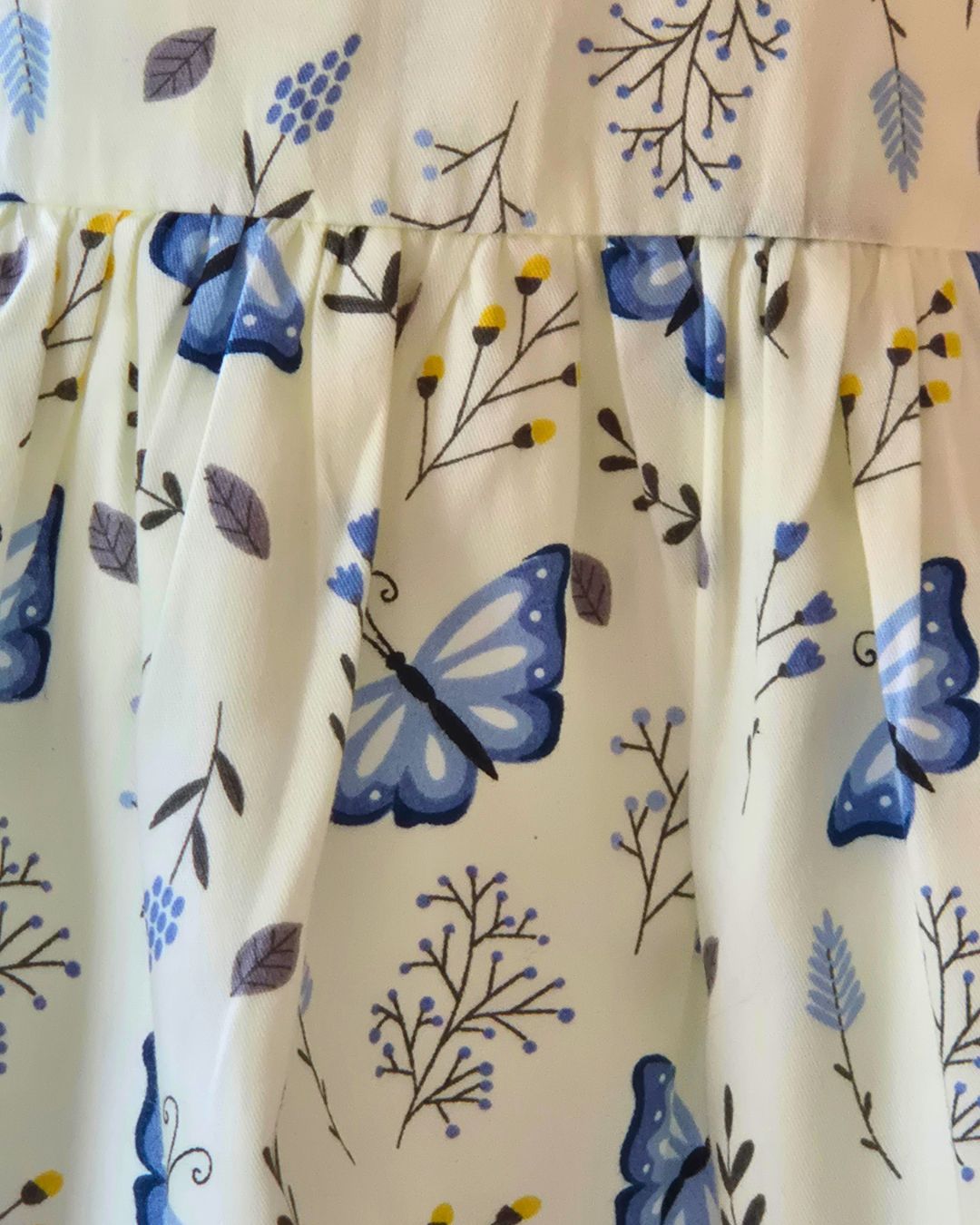 Girls cream dress with blue butterflies and blue and yellow flowers and ferns print