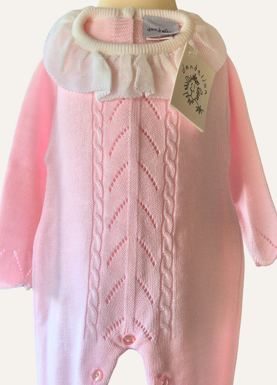Baby pink knitted romper with cable and lace detail and a white collar with matching bonnet from Dandelion