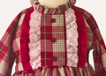 Close up detail of bodice on girls spanish red and beige tartan dress.