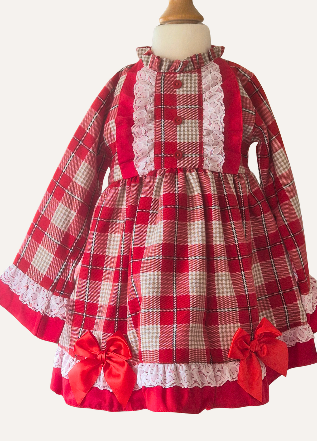 Spanish red, beige and white plaid dress with lace details and red bows on a mannequin.