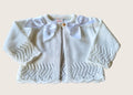 Ivory knitted cardigan with double satin bow details on a beige background
