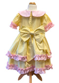 Back of a lemon dress with pink ruffles and an oversized lemon bow on a mannequin against a white background
