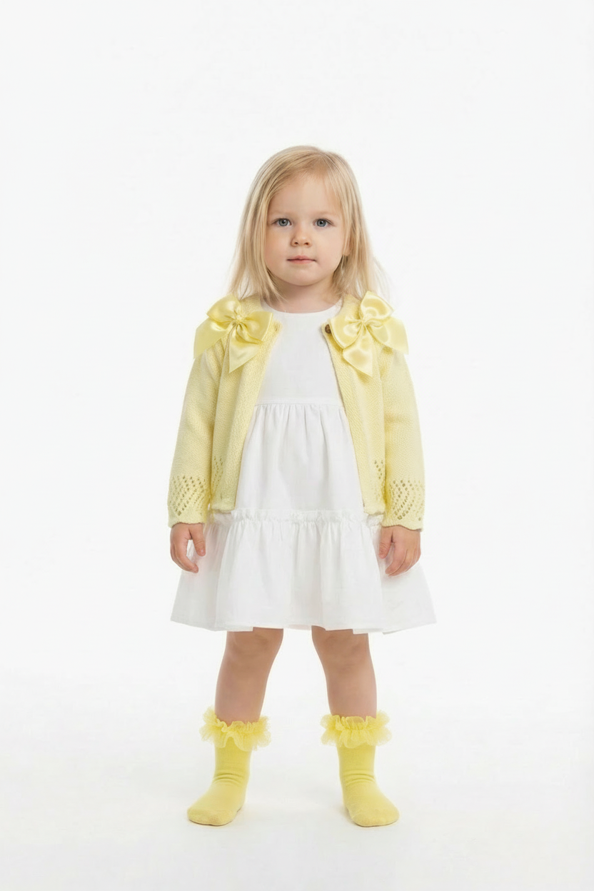 Lemon double bow cardigan on a blonde girl over a white frill dress