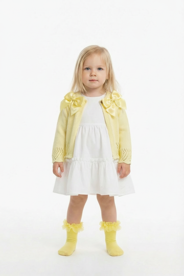 Lemon double bow cardigan on a blonde girl over a white frill dress