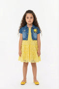 Young girl wearing a yellow lace dress with a denim shrug on a white background