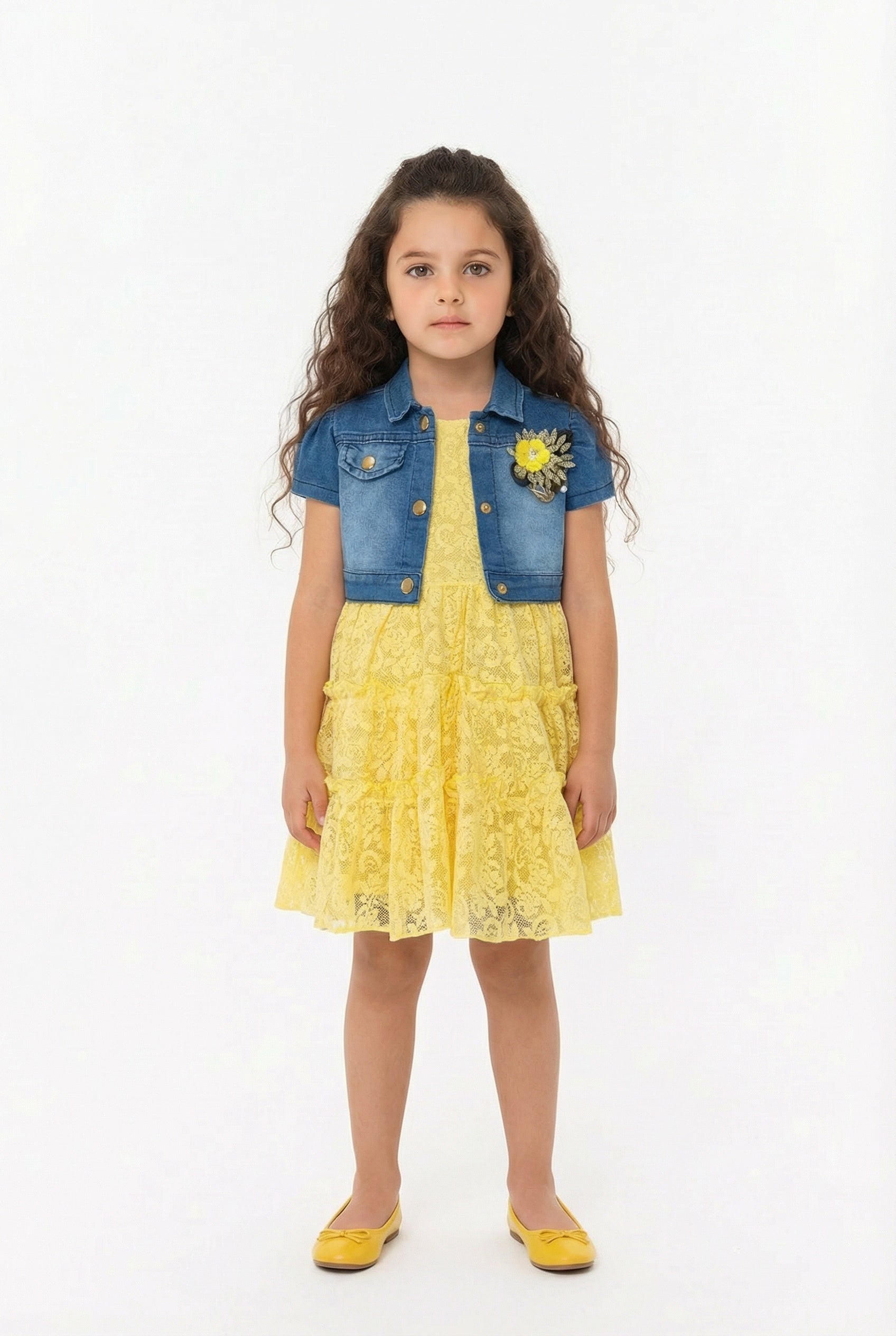 Young girl wearing a yellow lace dress with a denim shrug on a white background