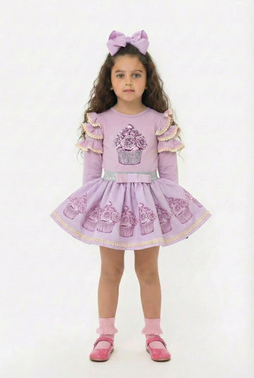 Young girl in a lilac co ordinating skirt and top set featuring a sparkly cupcake design.
