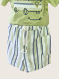 Children's outfit with green shirt and striped shorts on a beige background