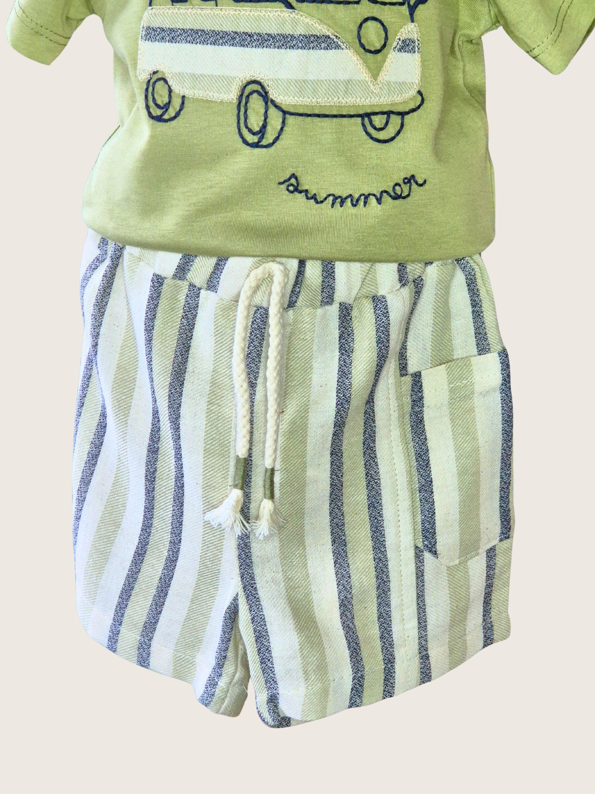 Children's outfit with green shirt and striped shorts on a beige background