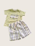Children's outfit with a green t-shirt and striped shorts on a light beige background