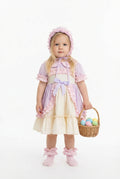 Young girl in a pastel dress holding a basket of Easter eggs on a white background