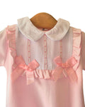 Baby pink sleepsuit with white bib and pink satin bows