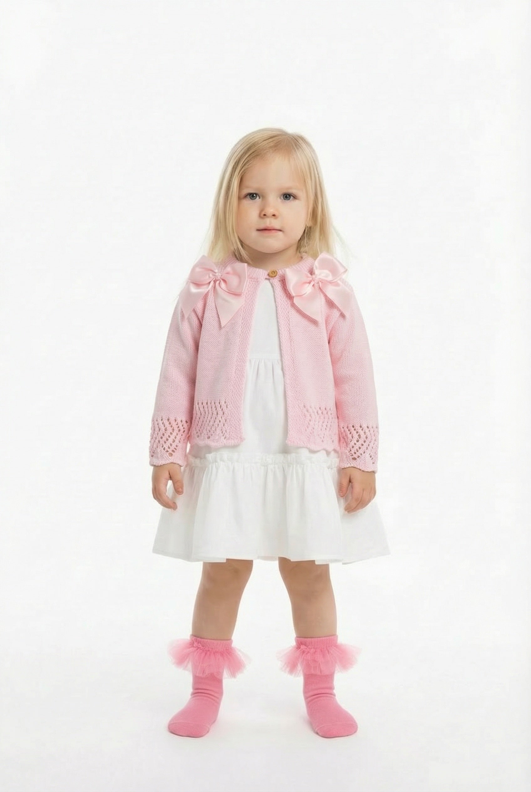 blonde girl in a white frill dress with a pink double bow cardigan on top