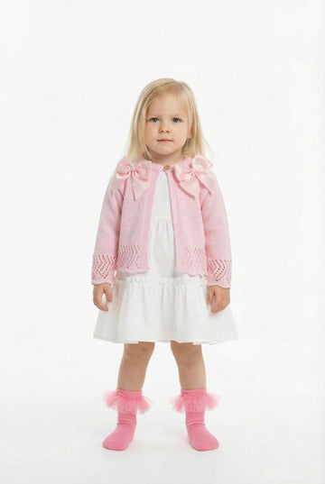 blonde girl in a white frill dress with a pink double bow cardigan on top