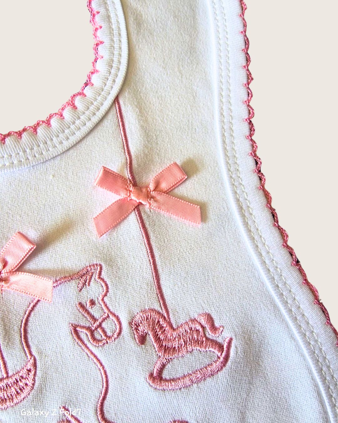 White baby bib with pink scalloped edging