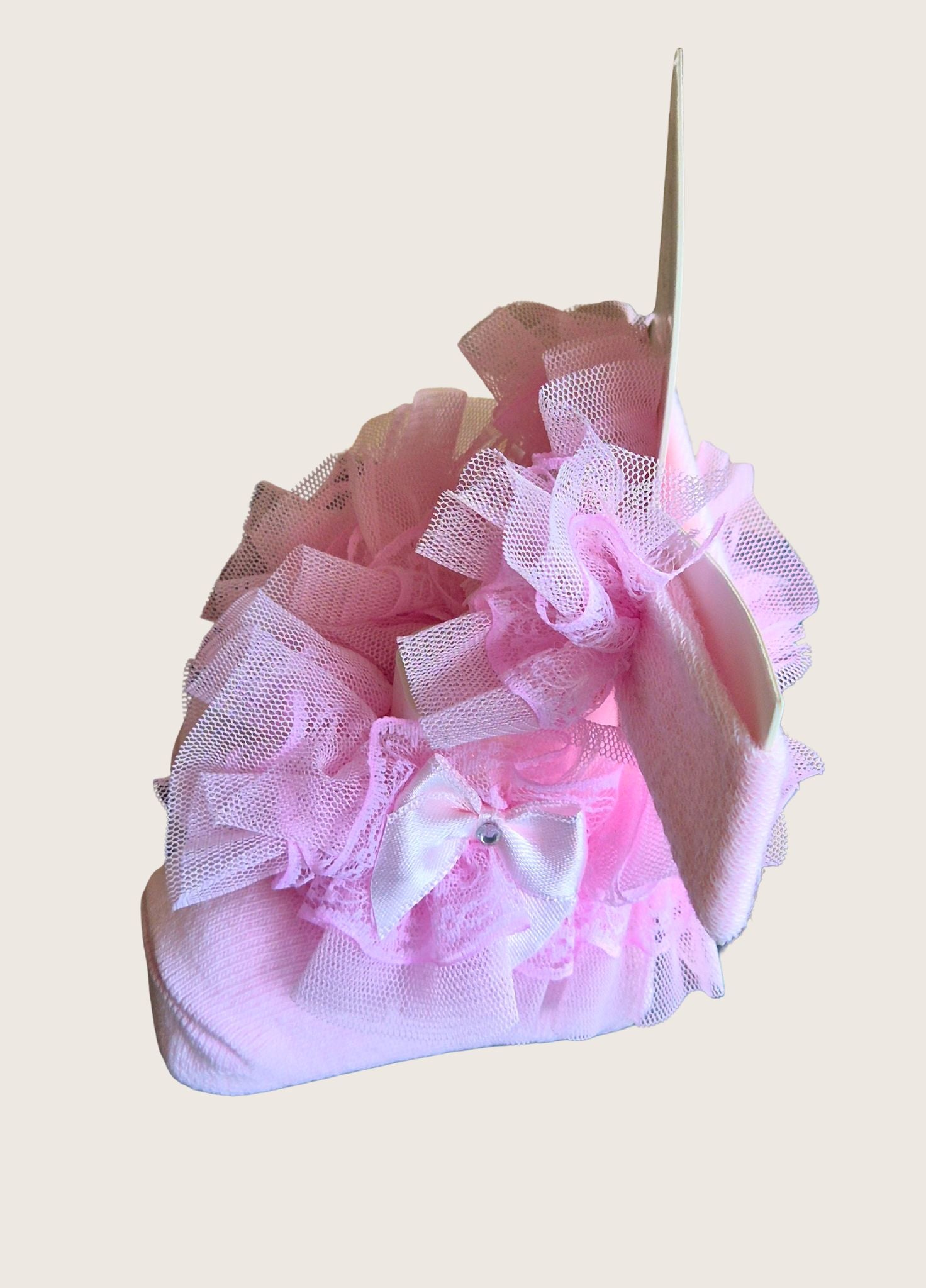 Pink decorative socks with ruffles and a bow and matching headband on a light pink background