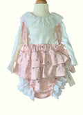 Children's outfit with pink ruffled romper and white top on a mannequin.