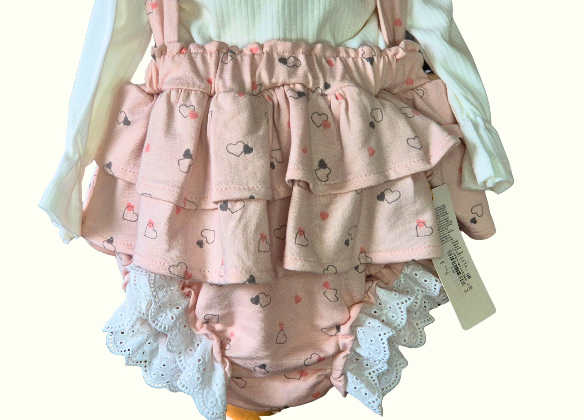 Pink ruffled baby bloomers with heart pattern on a white background
