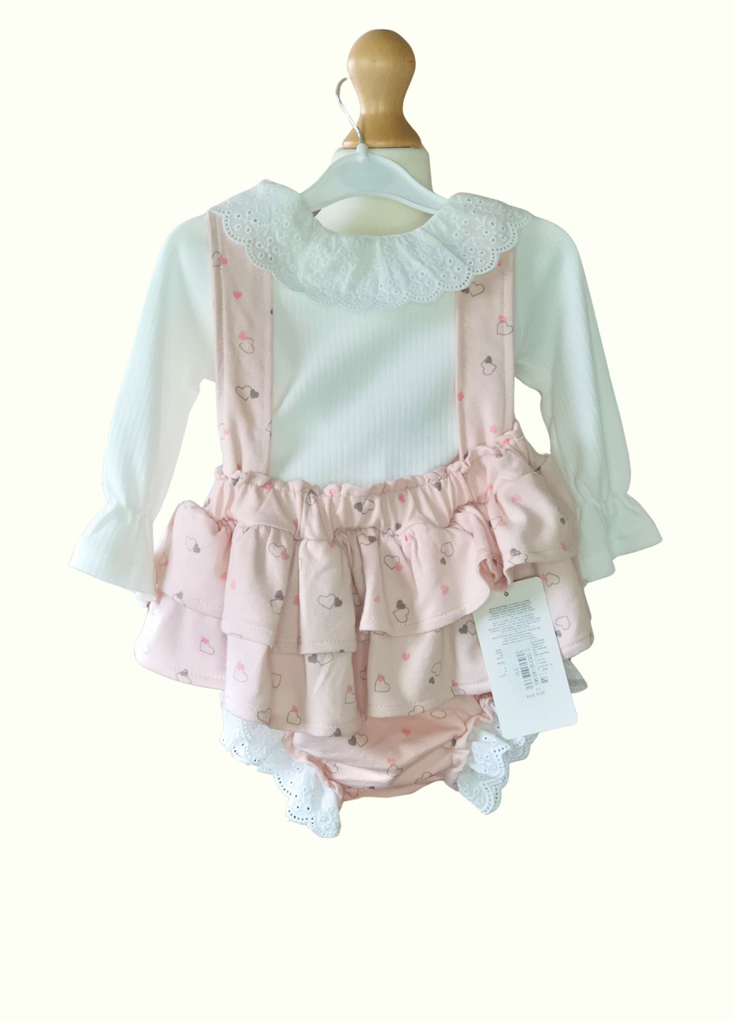 Baby outfit with pink ruffled bloomers and white long-sleeve shirt on a mannequin against a white background.