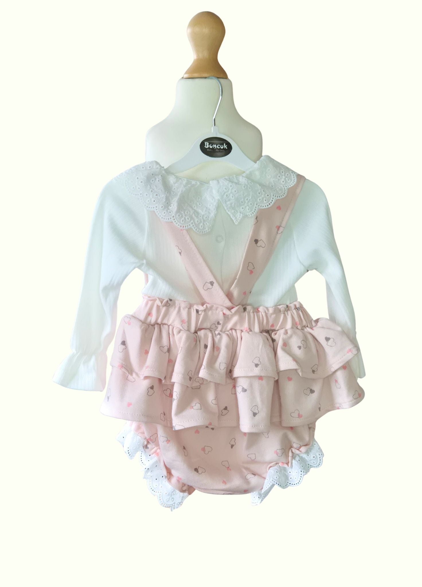 Baby outfit with white lace top and pink ruffled bloomers on a mannequin against a white background.