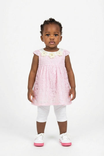 Young black girl wearing a pink lace dress with white flowers  and a paid of white leggings on a white background