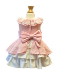 Pink and white dress tiered dress with an oversized pink bow at the back on a mannequin against a white background.