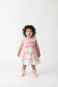 Child wearing a pink and white dress on a white background