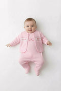Baby wearing a pink outfit with a matching jacket on a white background