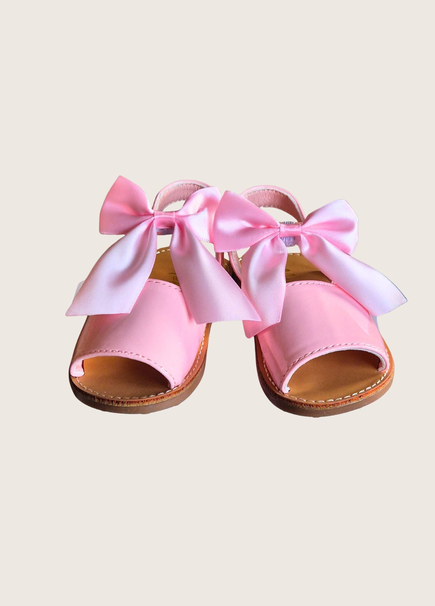 Pink sandals with large bows on a beige background