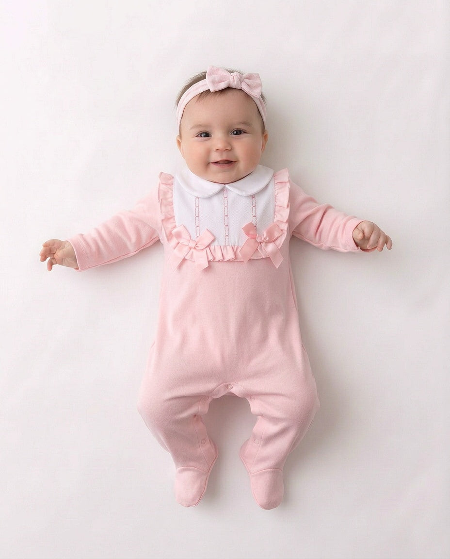 Pink and white baby sleepsuit with frilled bib and bows